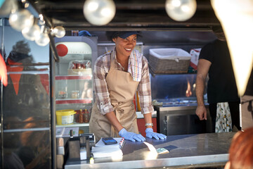 Fototapeta premium afro-american female employee in fast food service looking at customers with smile