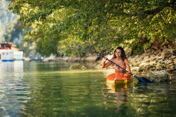 Female in bikini kayaking on lake during sunny day