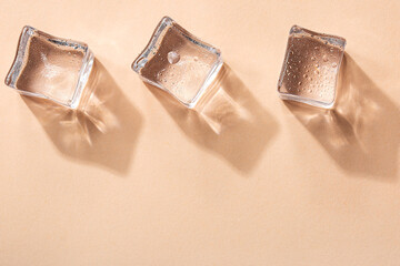 Three Ice cubes on pastel peach color background. Concept art. Minimal surrealism. Flat lay with copy space. Soft focus.
