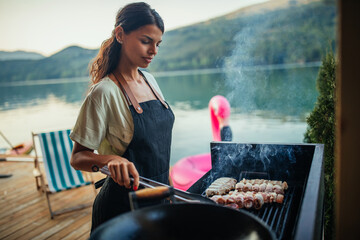 Lovely female grilling food at barbecue outdoors
