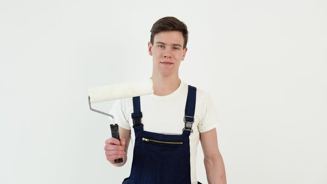 Painter with a roller in his hands looks at the camera