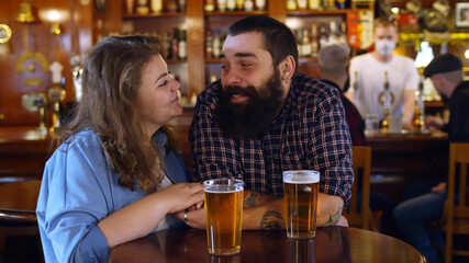 Couple in pub drinking beer, talking and having fun.