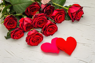 Fresh burgundy roses with felt hearts on a white putty background