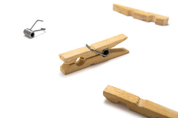 Wooden clothespin isolated on white background, surrounded by another clothes pin, disassembled into pieces. Close-up photo.