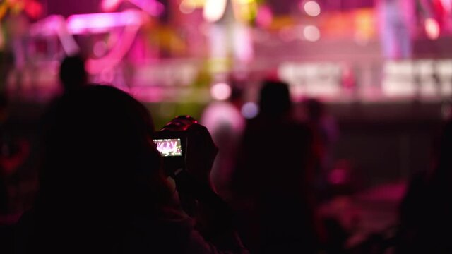 Music fan recording live performance concert with photo camera indoor.