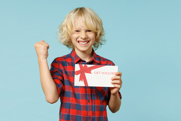 Joyful little curly kid boy 10s years old in basic red checkered shirt hold gift certificate doing...