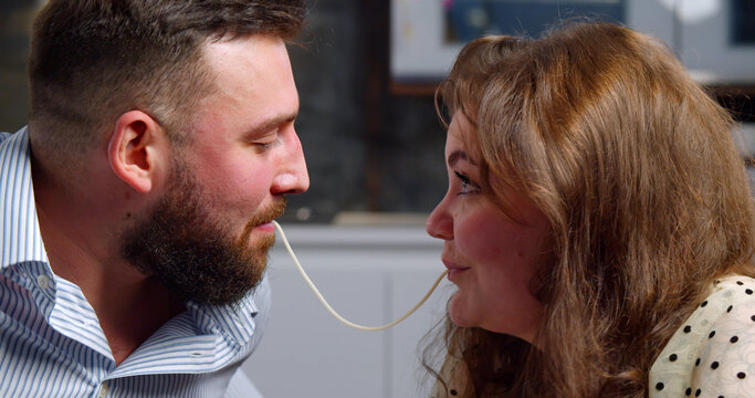 Side View Of Young Couple Eating Pasta And Kissing Enjoying Romantic Dinner