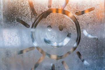 Smiley face drawn on a frozen window