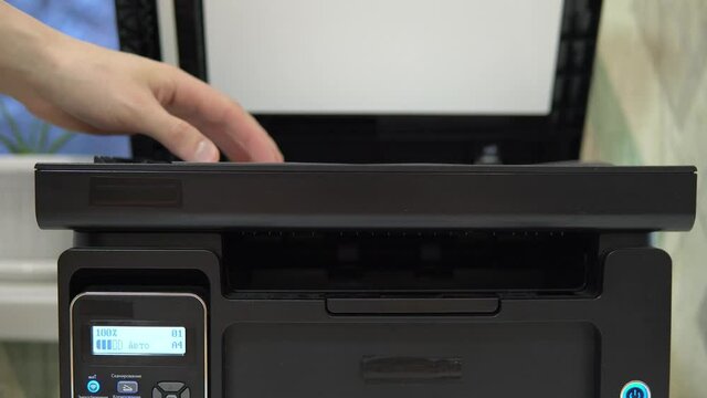 A man puts a document on the scanner to scan and tries to start