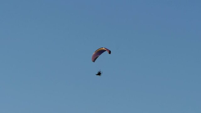 paraglider with a motor flies high in the blue sky