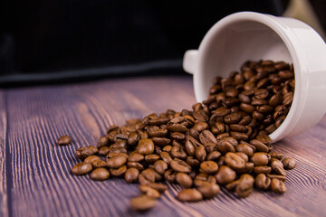 coffee beans sprinkled from a white cup on a wooden table