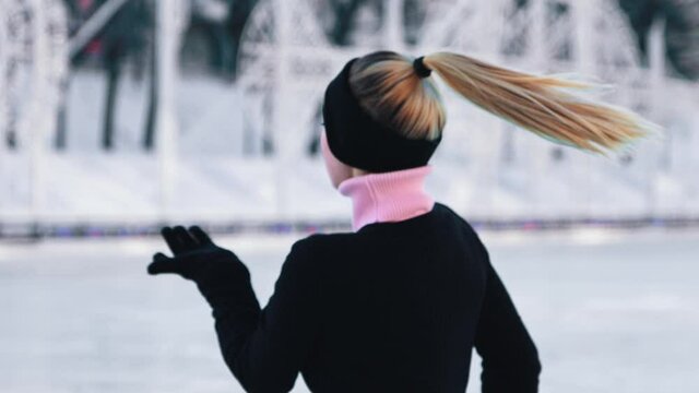 Young beautiful woman figure skating on ice rink and looking in the camera