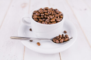 coffee beans in a white cup on a wooden table
