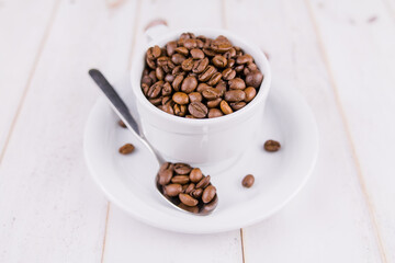 coffee beans in a white cup on a wooden table