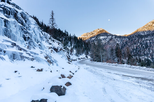 Ice forms on a sheer wall as the moon sets over the snow-covered San Juan Mountains near Ouray, Colorado

