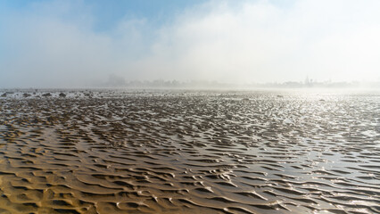 Fototapeta premium panorama landscape of fog lifting over an endless wadden sea beach at low tide