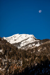 The moon hangs low in the sky over a snow-covered mountain peak in the San Juan Mountains near Ouray, Colorado
