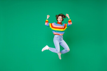 Fototapeta na wymiar Full length of happy joyful young brunette woman 20s years old wearing basic casual colorful sweater jumping doing winner gesture celebrating isolated on bright green color background studio portrait.