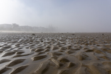 landscape of fog lifting over an endless wadden sea beach at low tide