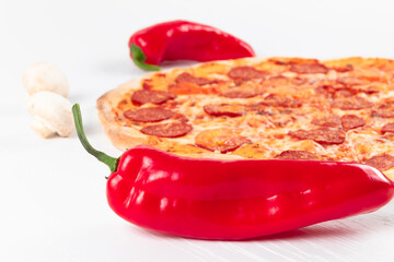 fresh aromatic hot italian pepperoni pizza with mozzarella cheese, red peppers and mushrooms on a white wooden table background