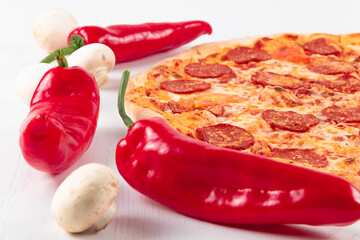 fresh aromatic hot italian pepperoni pizza with mozzarella cheese, red peppers and mushrooms on a white wooden table background