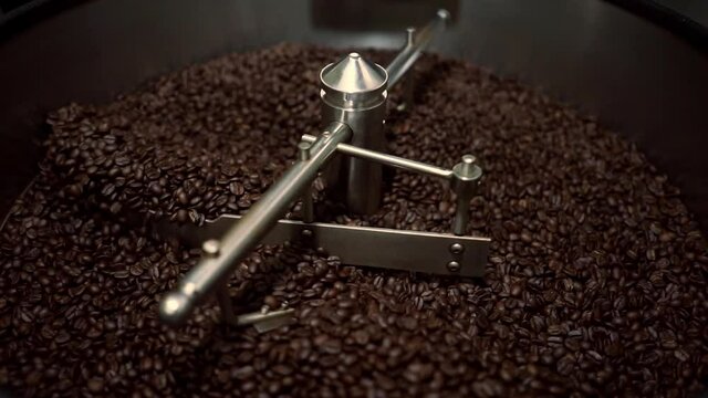 Process of roasting fresh fried arabica coffee beans. Coffee beans are mixed around an oven cooling plate.