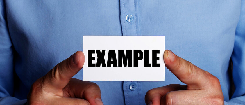 The word EXAMPLE is written on a white business card in a man's hands. Business concept