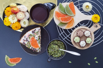 Cake with coffee, sweets, pumpkin seeds and flowers on a dark background. Selective focus