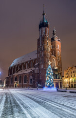 St Mary's church on snow covered Main Square in winter Krakow, illuminated in the night