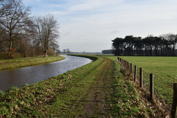 Fototapeta na wymiar Beautiful Netherlands canal in the countryside with trees and footpath on the riverbank