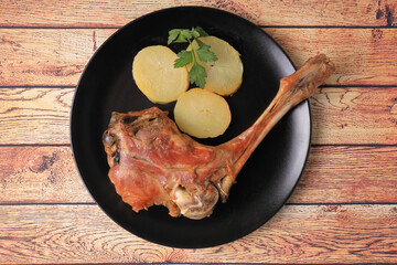 Oven roasted leg of lamb or kid garnished with potatoes and parsley