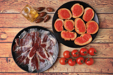 Portion of acorn-fed Iberian ham accompanied by slices of bread with crushed tomato