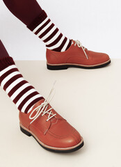 Unrecognizable woman legs wearing retro  brown shoes and stripped socks. Fashion vintage shop concept