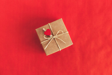 Craft gift box with red heart on a red background. Holiday concept for Valentine's day.