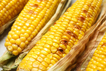 Delicious grilled sweet corn cobs on table, closeup