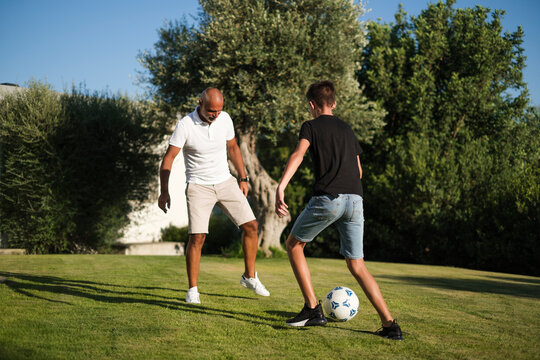 Padre e figlio giocano a pallone nel prato del giardino di casa