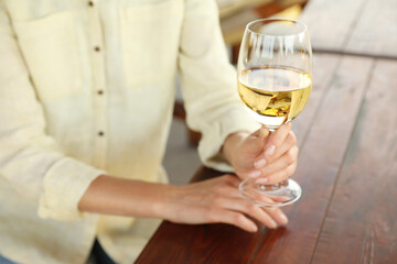Woman with glass of white wine in outdoor cafe, closeup