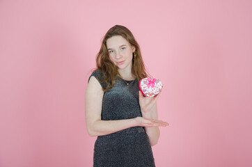 girl holding a gift in her hands on a pink background. concept valentines day, christmas, childrens day, womens day