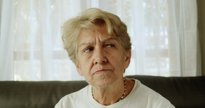 A medium close-up shot of an senior woman after retirement cut short hair with light brown hair is showing a hesitant expression.