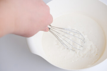 hand holding a whisk and mixing a panna cotta dessert. homemade traditional italian meal. tasty sweet dessert made of cream. dairy product. easy recipe. 