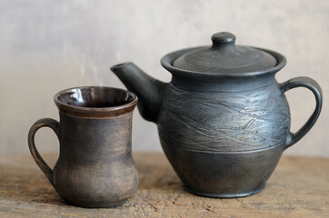 A table on which there is a mug of tea and a kettle.