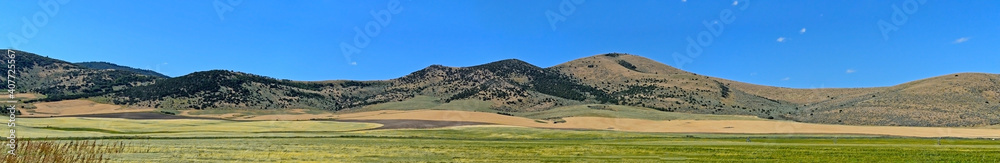 Poster panoramic shot of mountains and agricultural fields under the blu sky