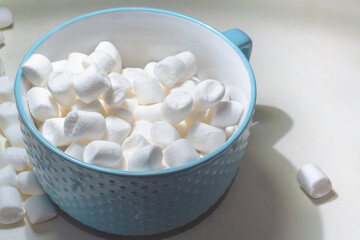 Fototapeta na wymiar White sweet marshmallow marshmallows in a blue plate on the table.