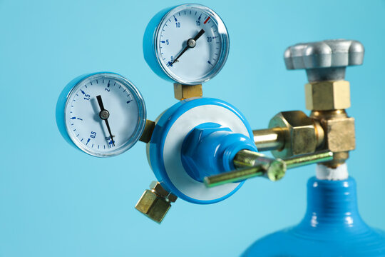 Pressure gauge of medical oxygen tank on light blue background, closeup
