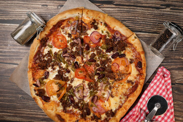 Top view of fresh baked pizza with meat and vegetables on a wooden table. Pizza delivery. Take away.	
