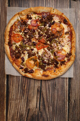 Top view of fresh baked pizza with meat and vegetables on a wooden table. Pizza delivery. Take away.	
