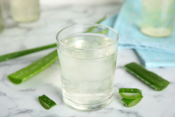 Fresh aloe drink in glass on white marble table, closeup