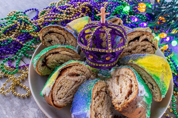 sliced Mardi Gras king cake with baby surrounded by colorful beads © Lynne Ann Mitchell