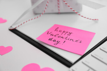 Memory sticker with phrase Happy Valentine's Day on clipboard at table, closeup