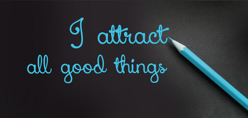 I attract all good things - positive affirmation words - handwriting on a black paper with blue...